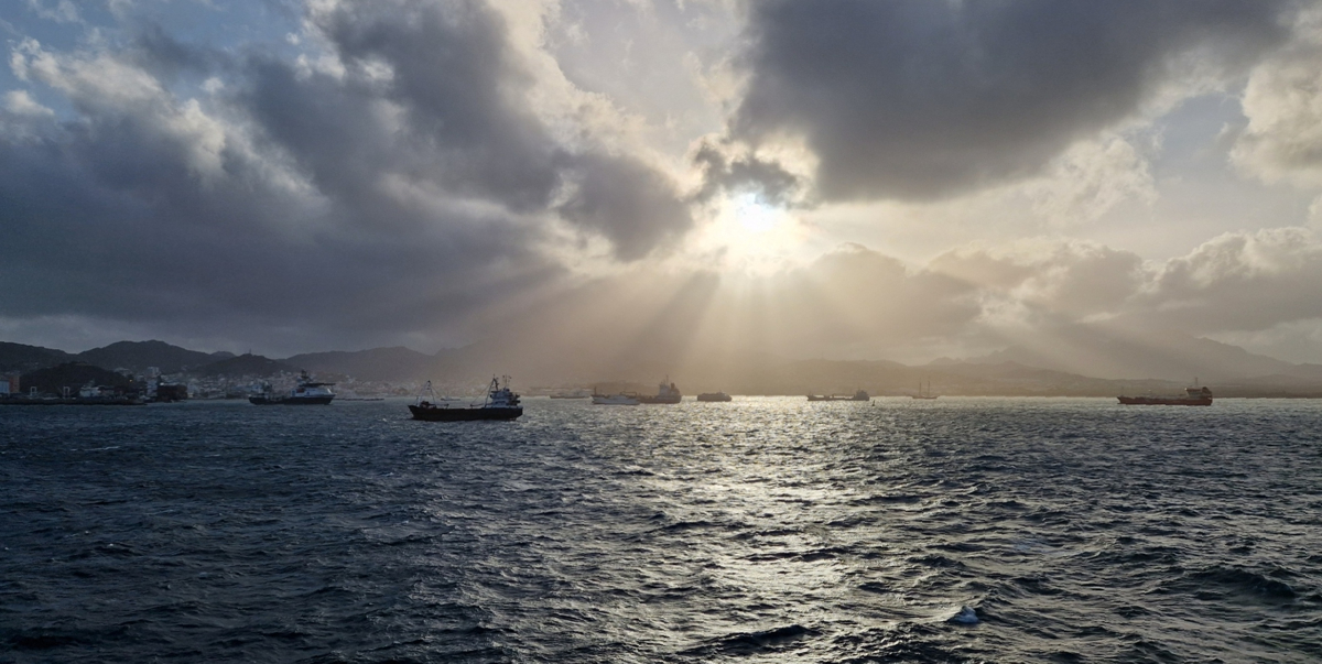 The sun pierces through the clouds and through the dust that is blowing through the air of Mindelo harbour